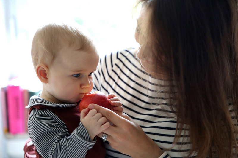 Mutter füttert Kind mit Apfel