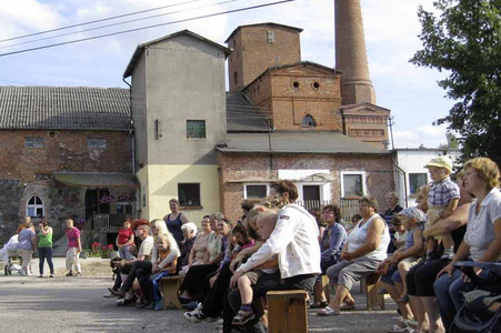 Besucher vor einem der Gebäude des Dorfprojekts