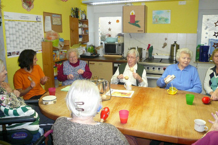 Elder people and caregivers sitting together around a big oval and wooden table