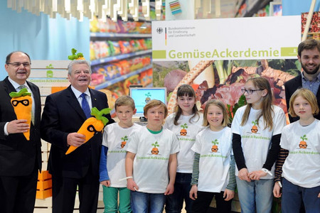Group photo with President Joachim Gauck, agriculture minister Christian Schmidt and some children, all holding the mascot of GemüseAckerdemie in hand, a carrot with glasses