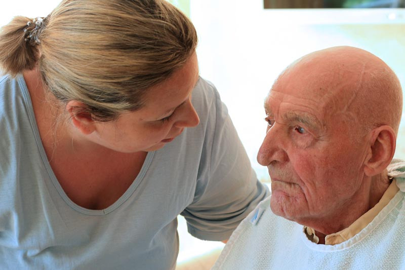 A care taker and an older man at lunch