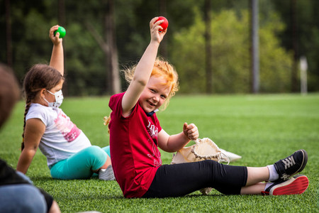 Rothaariges Mädchen hält roten Ball in die Luft