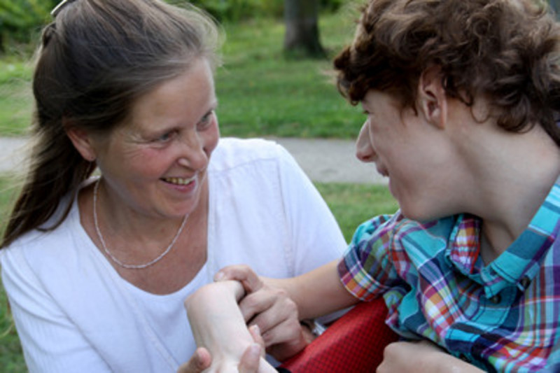 A woman and a boy with handicap laughing at each other