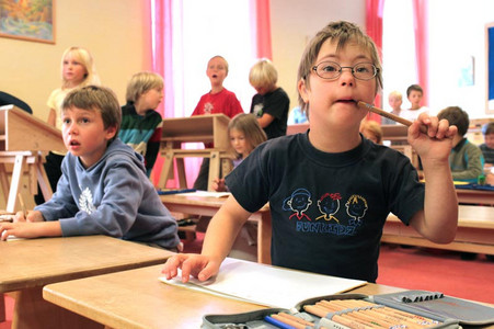 Junge Schüler mit und ohne Behinderung beim Unterricht in einem Klassenzimmer