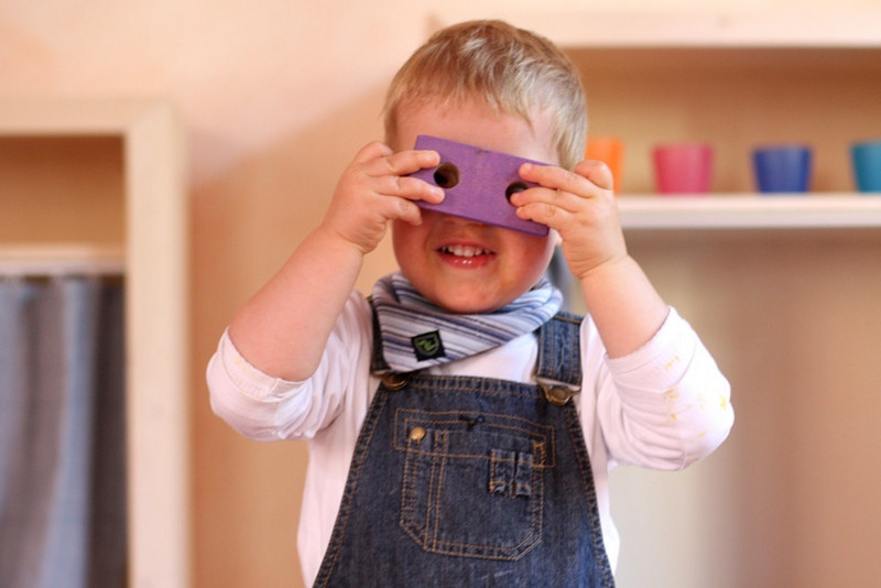 A child looking through a wooden building brick