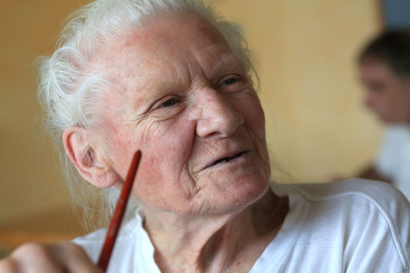 An older women laughing is holding a brush