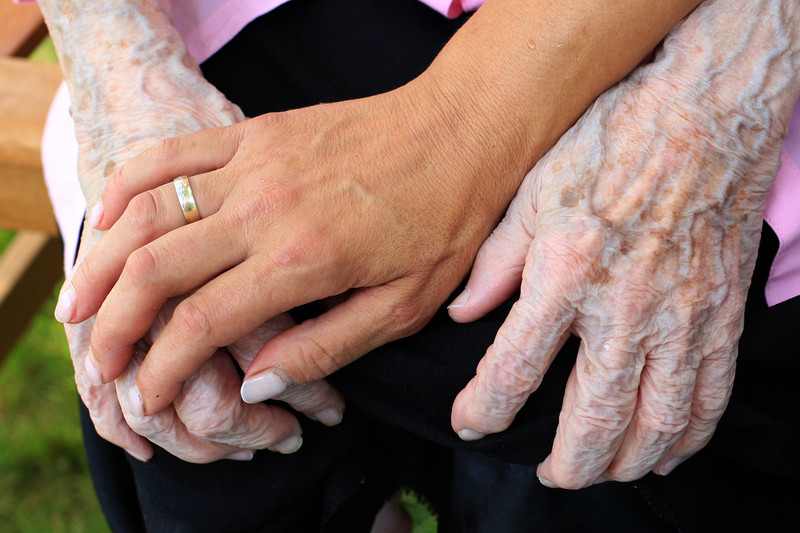 Junge Hand auf alter Hand