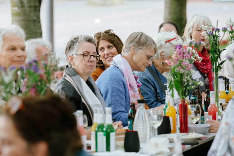 Gruppe von Menschen im Gespräch an einer langen Tafel