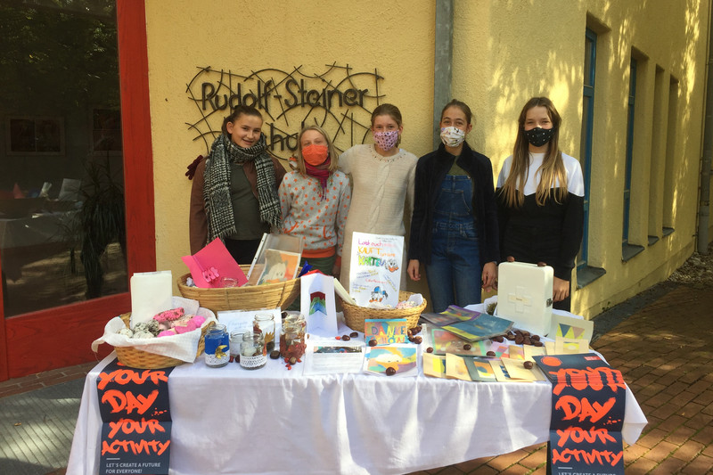 Mädchen mit Mundschutz hinter einem Verkaufsstand