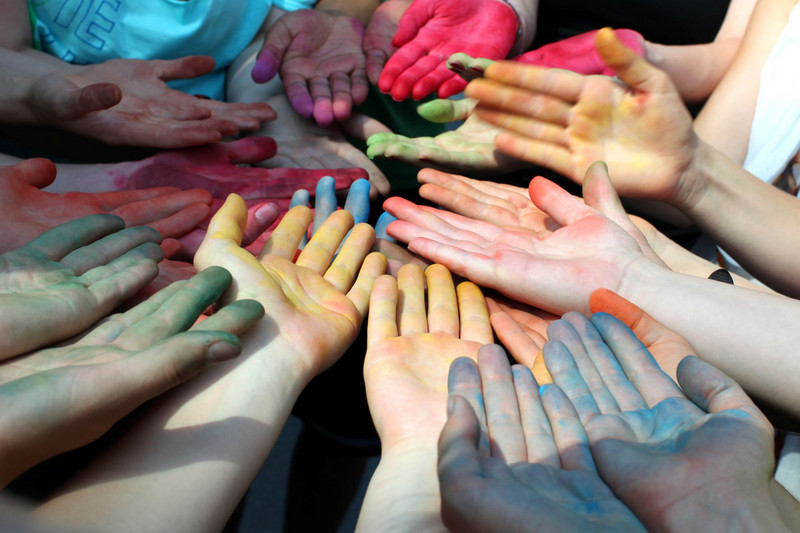 Colorfully painted children's hands hold together
