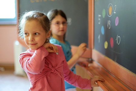 Ein Mädchen steht an einer Tafel und schaut über die Schulter