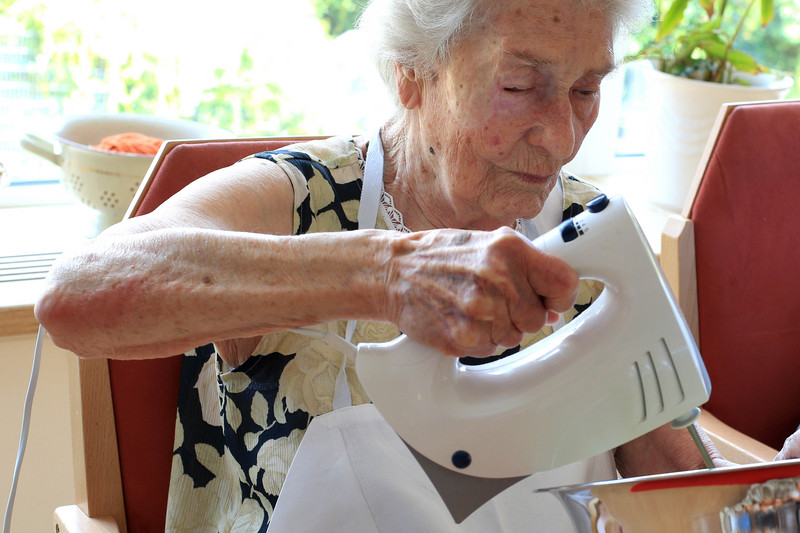 Elderly lady stirring dough