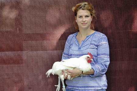 Inga Güther, managing director Ökologische Tierzucht holding a white chicken on her arms