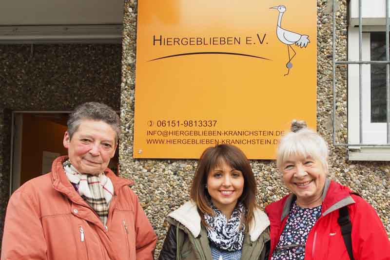 Three project workers in front of the entrance sign