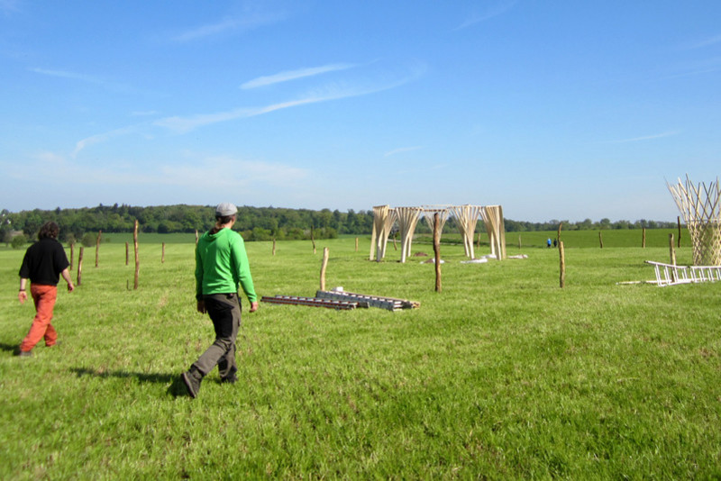 Die Fußelemente der Skulptur stehen auf einem mit holzpfählen abgesteckten Teil der Wiese