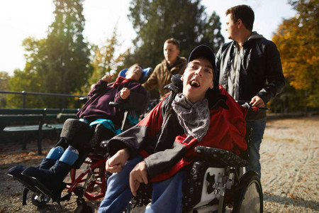 People with complex disabilities are pushed in a wheelchair