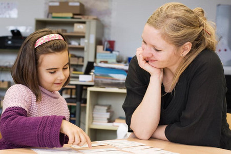 Eine Schülerin und eine Lehrerin sitzen zusammen an einem Tisch im Klassenraum bei der Lernbegleitung