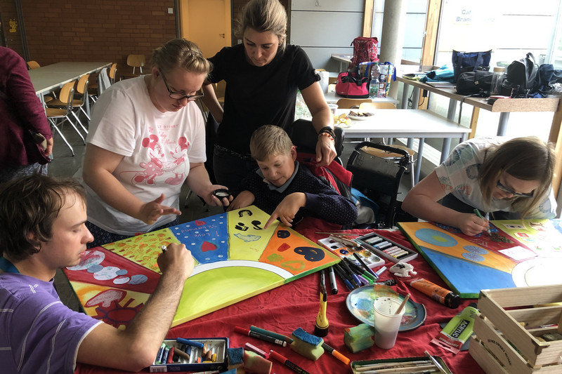 Menschen mit Assistenzbedarf sowie Betreuerin beim Lernen für die Wohnschule