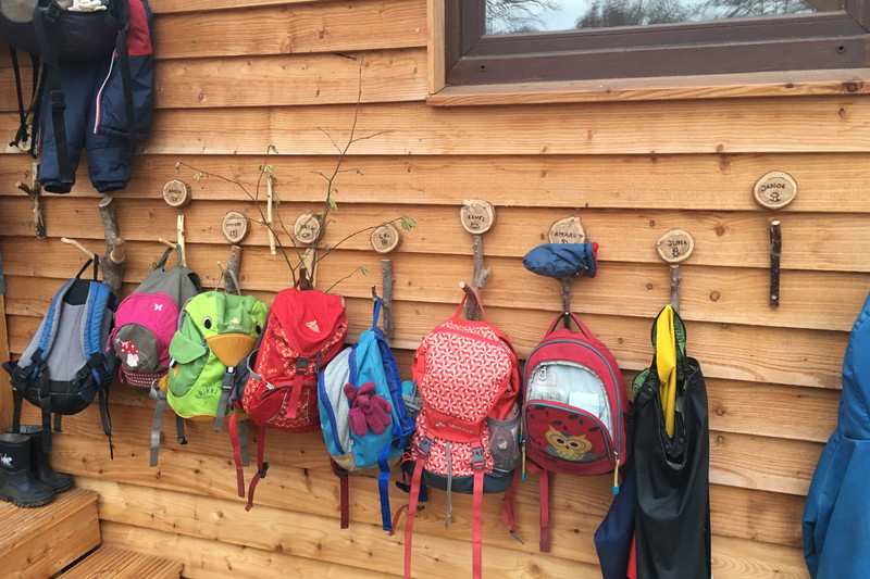 Bunte Kinderrucksäcke hängen außen am hölzernen Bauwagen