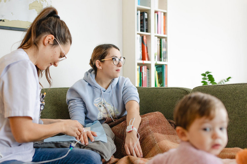 Pflege in den eigenen vier Wänden: Pflegerin mit Mutter und Kind