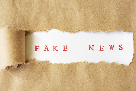 Zerrissenes Backpapier, unter dem Fake News hervorlugt 