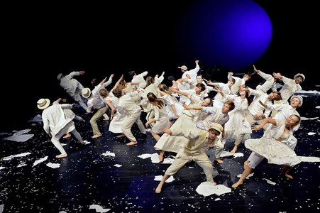 Youths in white clothing performing on a stage