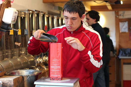 Ein Mitarbeiter der Rösterei füllt geröstete Kaffeebohnen in eine Verpackung