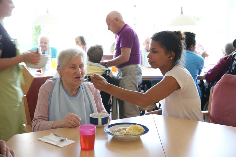 Residents and caregivers eating in the dining room