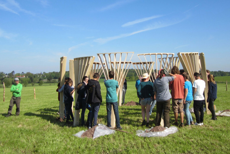 Gemeinsam stellen die Jugendlichen die Füße der Holzskulptur auf